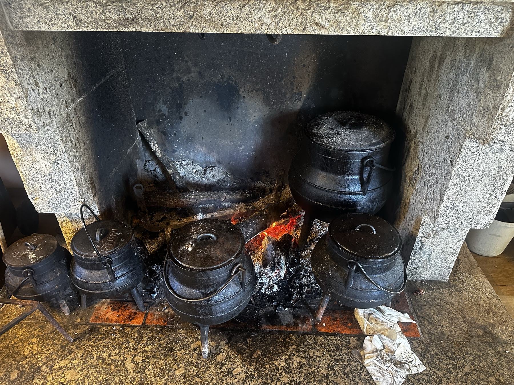 Potes de ferro ao lume numa lareira de granito
